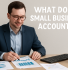 A professional accountant in a navy suit and light blue shirt reviews financial documents, including a "FINANCIAL REPORT" and pie charts, while smiling. The image includes the text overlay: "WHAT DOES A SMALL BUSINESS ACCOUNTANT DO?"
