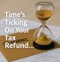 Hourglass with golden sand placed on an HMRC envelope over tax forms, symbolising delays in self assessment tax refunds, with overlay text reading ‘Time’s Ticking On Your Tax Refund…’