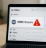 Laptop screen displaying an urgent "HMRC Enquiry" email notification with a red warning icon, symbolising the start of a tax investigation.