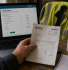 UK contractor reviewing CIS return on laptop with paper invoice and high-vis jacket — construction accounting 2026