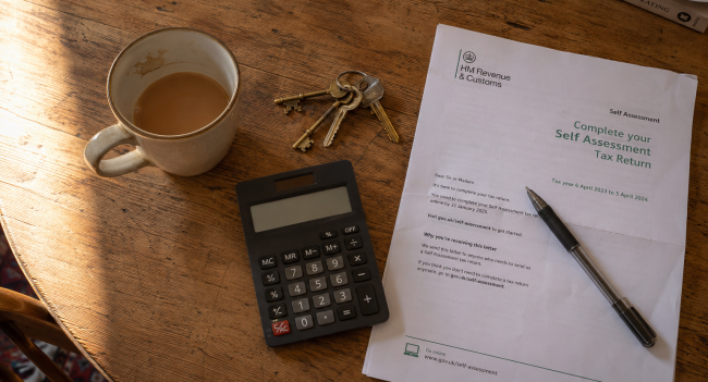 Tax on rental income UK paperwork on kitchen table with HMRC self assessment letter and house keys